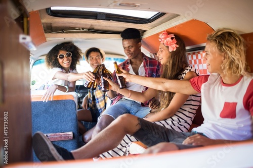 Happy friends toasting beer bottles in camper van photo