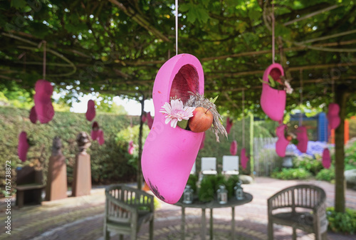 Pink clogs filled with flowers and apples hung on a tree to decorate the garden photo