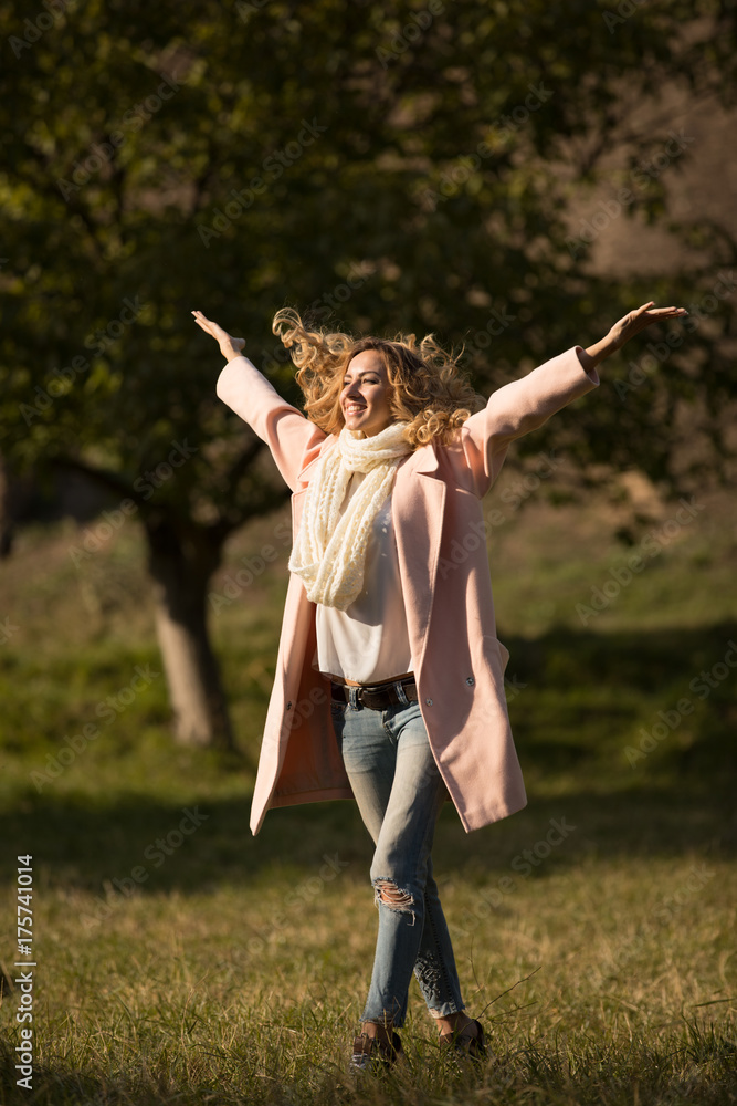 Full-length portrait of smiling woman in autumn day at park, she enjoying autumn day with raised hands Full-length portrait of smiling woman in autumn day at park, she enjoying autumn day with raised hands