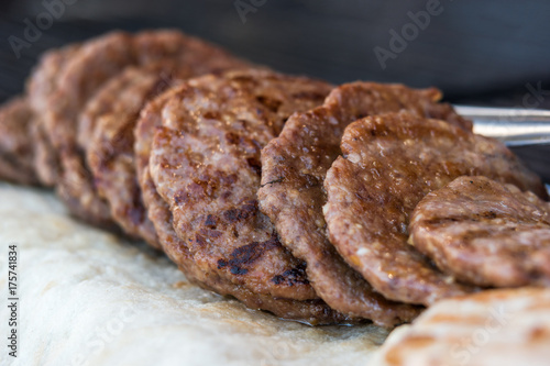 grilled pljeskavica stacked on a fair stall, selective focus photo