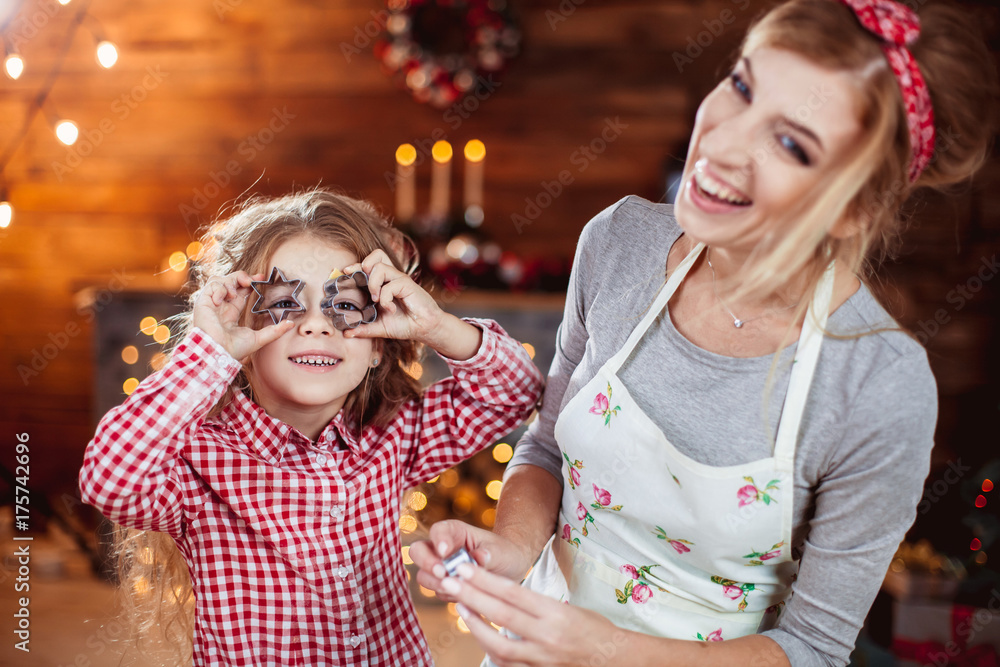 Obraz premium Merry Christmas and Happy Holidays. Family preparation holiday food. Mother and daughter cooking cookies in New Year interior with Christmas tree.