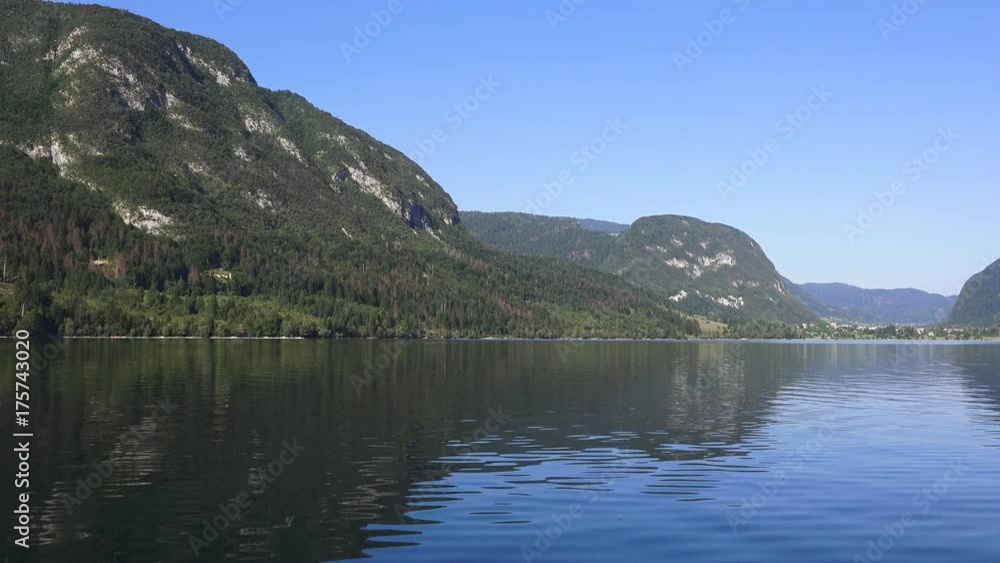 Sailing on Bohinj lake, Slovenia. Boat making waves on clear blue water surface. Summer vacation and holiday background. Sailing on Bohinj lake, Slovenia. Boat making waves on clear blue water surface. Summer vacation and holiday background.