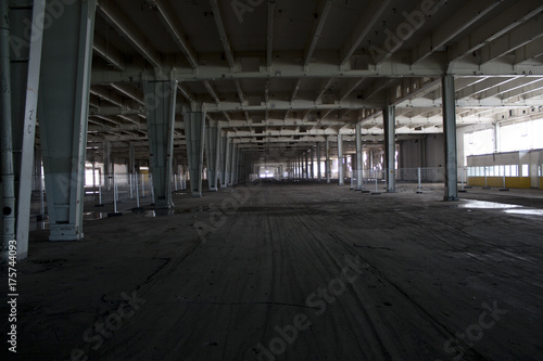 verlassene Industriehalle mit grauen Stahltr  gern und Fahrspuren am Fu  boden