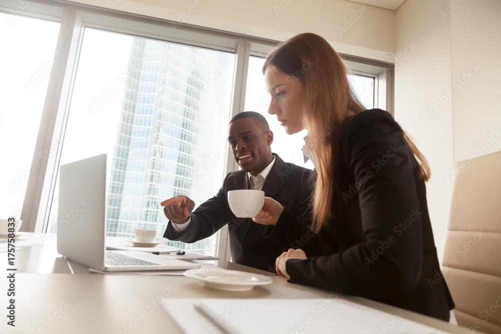 Φωτογραφία Afro american business adviser pointing on laptop screen at negotiations with white businesswoman in office
