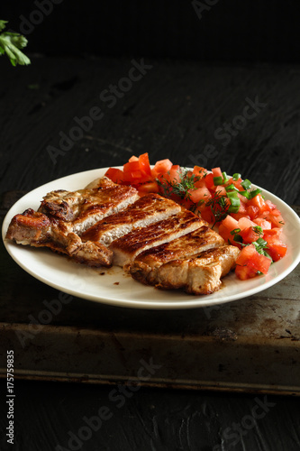 pork steak with tomatoes on a white plate