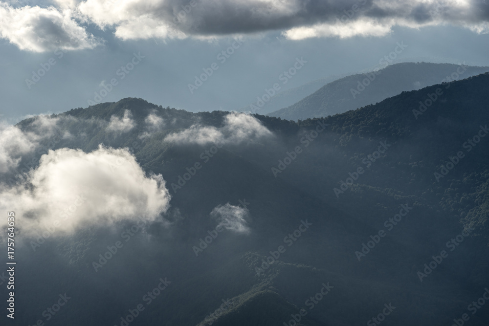 mountain landscape on the blue sky background and white clouds with sun rays