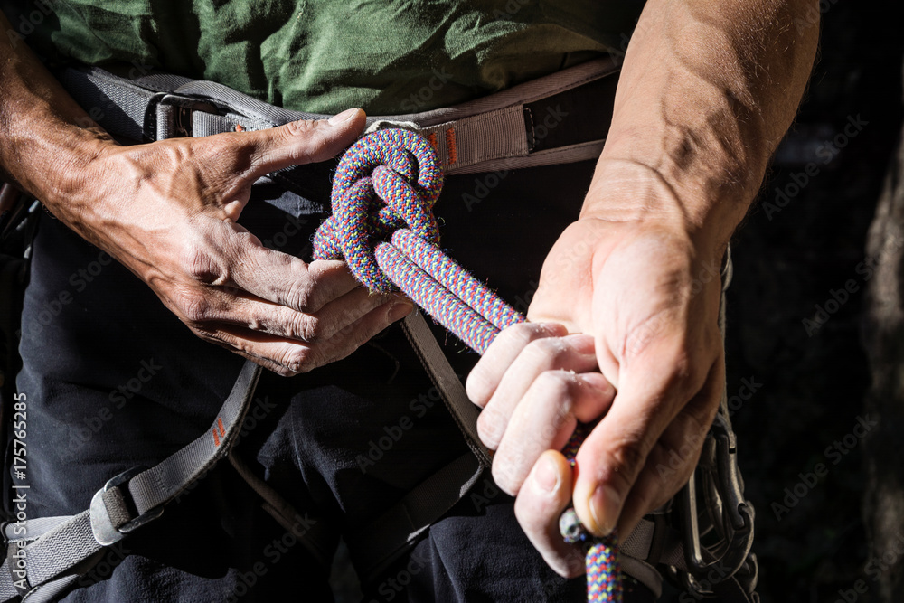 mountain climber tying rope in double bowline knot Stock Photo