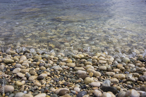 Closeup pebble stones on a beach with soft focus by the sea, waves and skyline
