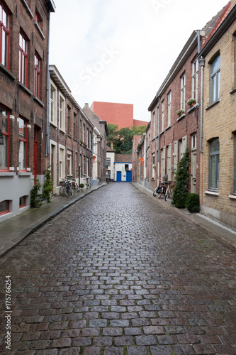 Quaint cobblestone street lined with old houses in Bruges Belgium. Bicycles leaning up against the walls. Quiet little street in a small European town.