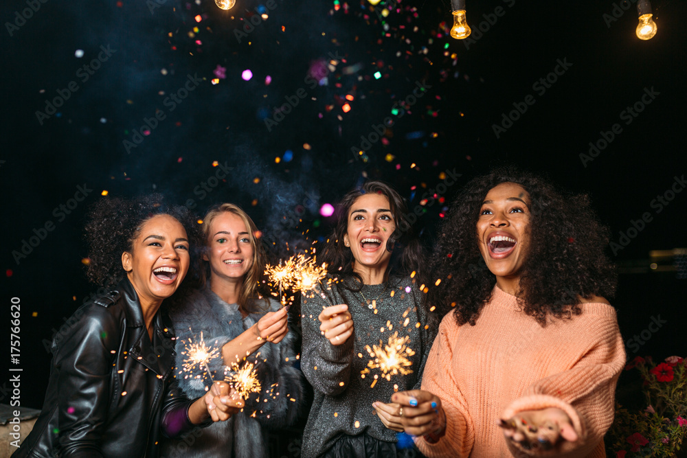 Female friends having party at night outdoors, throwing confetti - obrazy, fototapety, plakaty 