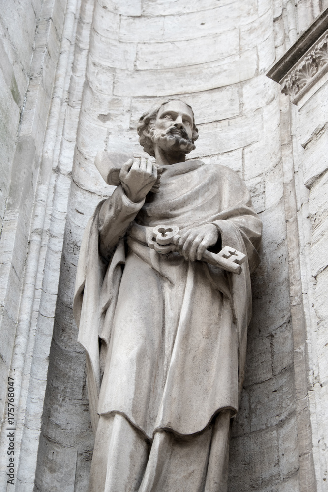 Statue of Saint Peter holding the key to the kingdom on his left hand. Stone statue of St Peter in a nook of the cathedral exterior in Antwerp Belgium. Facade of a church in Belgium Europe.