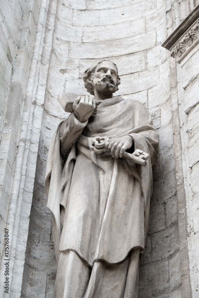 Statue of Saint Peter holding the key to the kingdom on his left hand. Stone statue of St Peter in a nook of the cathedral exterior in Antwerp Belgium. Facade of a church in Belgium Europe. Statue of Saint Peter holding the key to the kingdom on his left hand. Stone statue of St Peter in a nook of the cathedral exterior in Antwerp Belgium. Facade of a church in Belgium Europe.