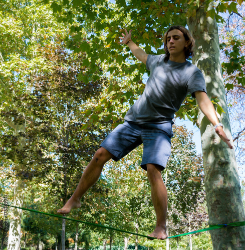 Billede på lærred Joven haciendo slack line deporte espiritual como el yoga de balance sobre una c