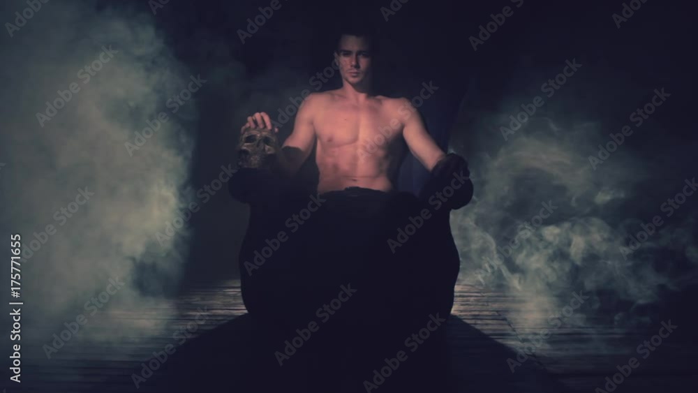 Sexy man sitting in a chair with a skull in the smoke Sexy man sitting in a chair with a skull in the smoke