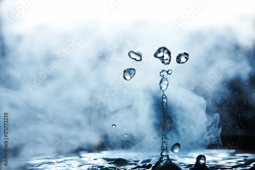 Fotografie Boiling water splash with steam on black background closeup