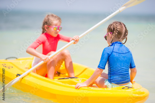 Little adorable girls enjoying kayaking on yellow kayak