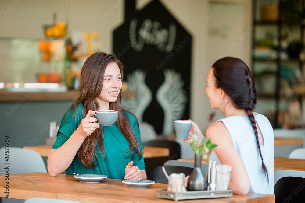 Happy smiling young women with coffee cups at cafe. Communication and friendship concept Happy smiling young women with coffee cups at cafe. Communication and friendship concept