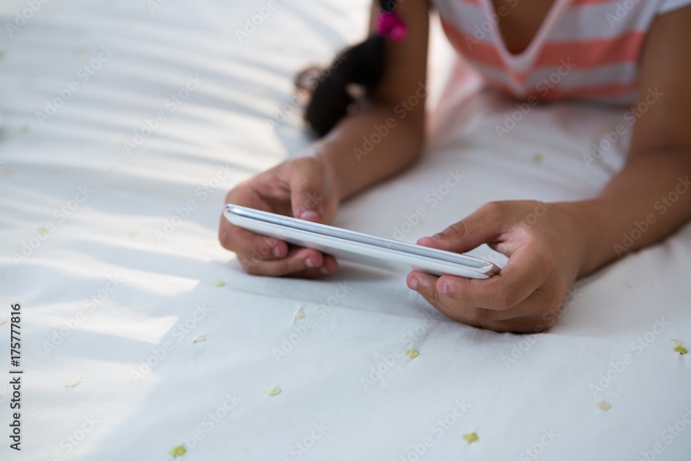 Midsection of girl using mobile phone on bed Midsection of girl using mobile phone on bed