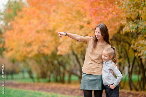 Little girl with mom outdoors in park at autumn day