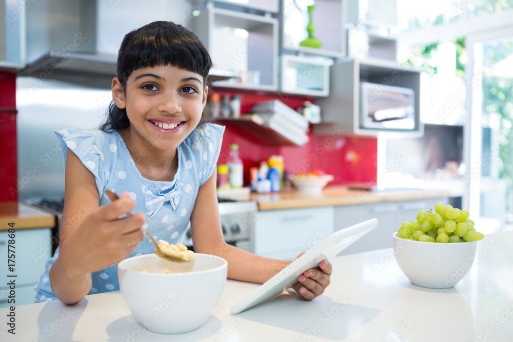 Portrait of girl eating breakfast with digital tablet in kitchen Portrait of girl eating breakfast with digital tablet in kitchen