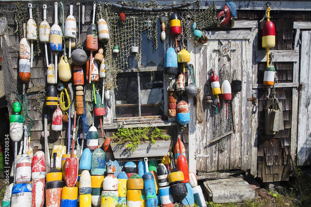 Obraz premium fishing wooden house with nets and buoys. colorful lobster buoys and fishnets hanged on wooden wall