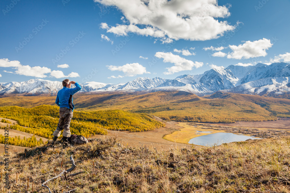 A Man looking at the Mountains and a Lake below from Viewpoint.
