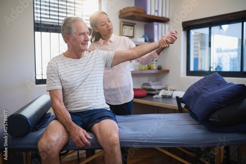 Female doctor examining wrist of senior male patient