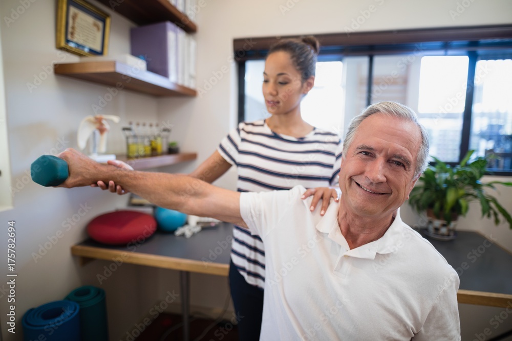 Obraz premium Female doctor holding hand of smiling senior male patient