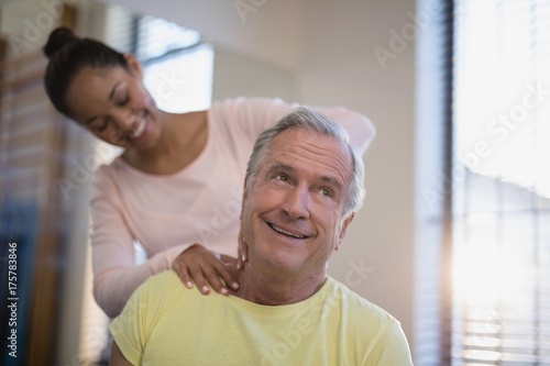 Smiling senior male patient receiving neck massage from