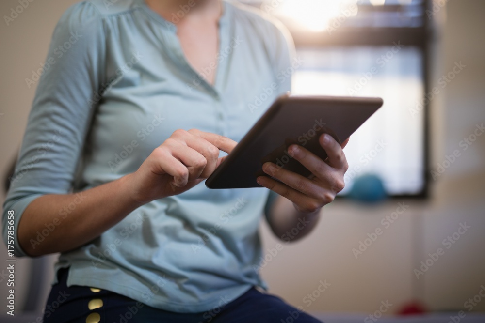 Midsection of female therapist using digital tablet