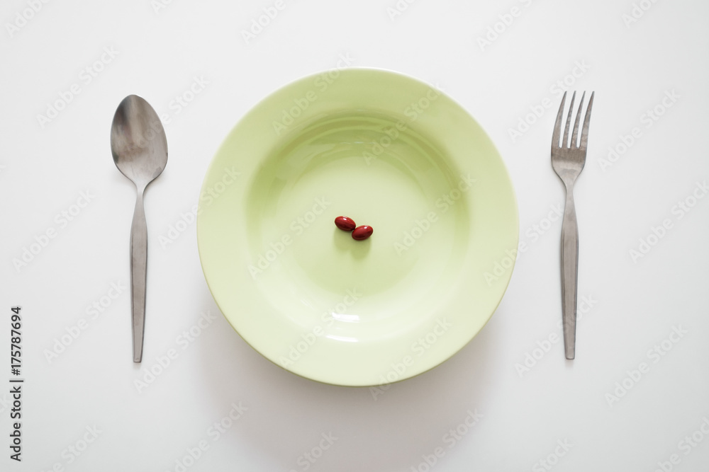 Fototapeta Pokarm uzupełniający na talerzu z widelcem i łyżką na białym stole