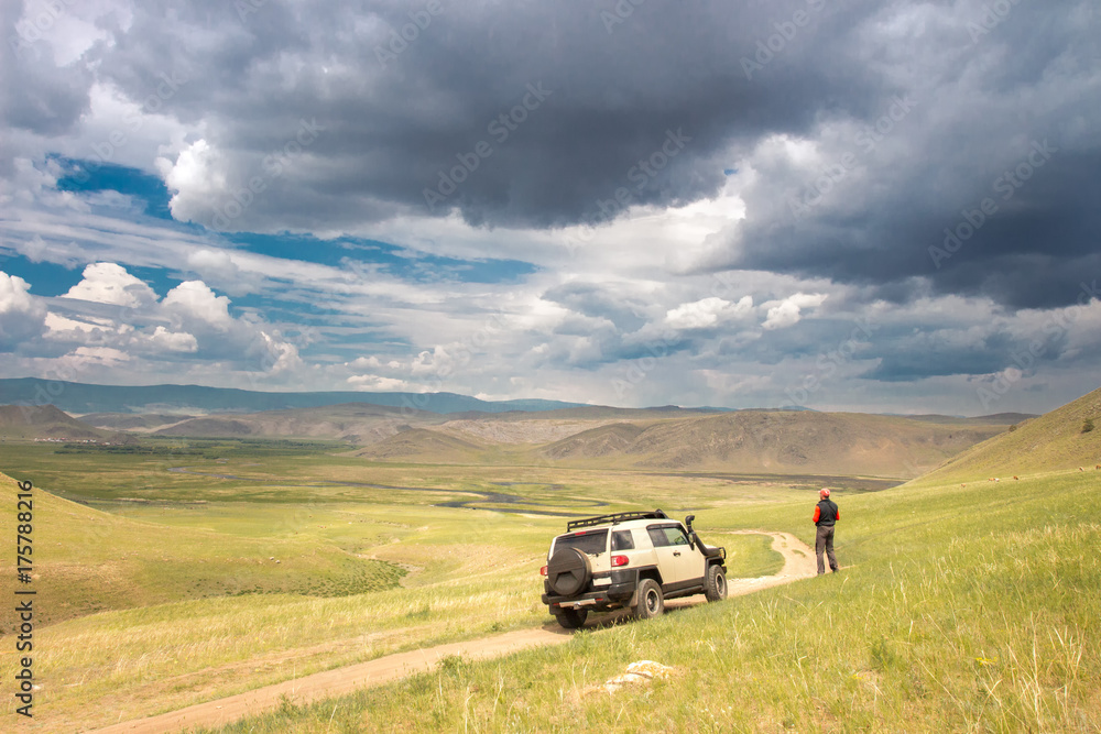 The car rides along a beautiful field