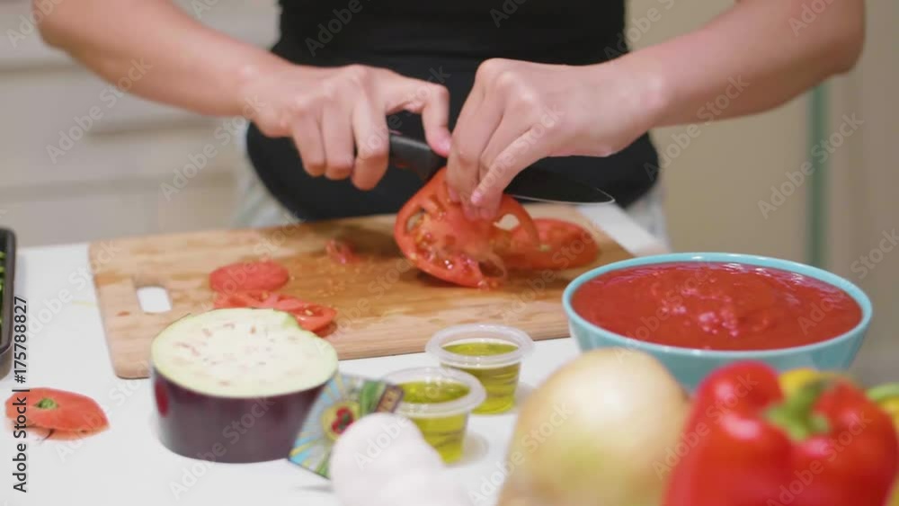 Cutting a red tomato on a cutting board Cutting a red tomato on a cutting board