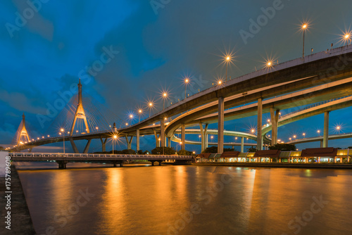 Blue twilight twin suspension bridge water front, cityscape background.