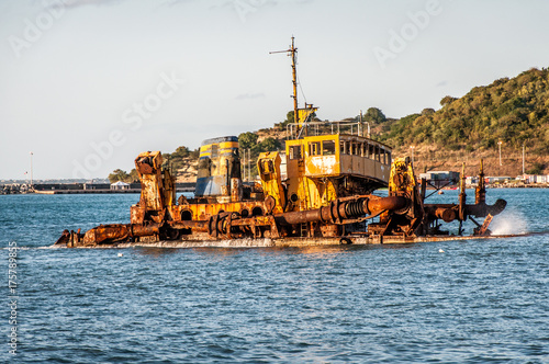 Rusting ship hull partially sunk in the ocean.