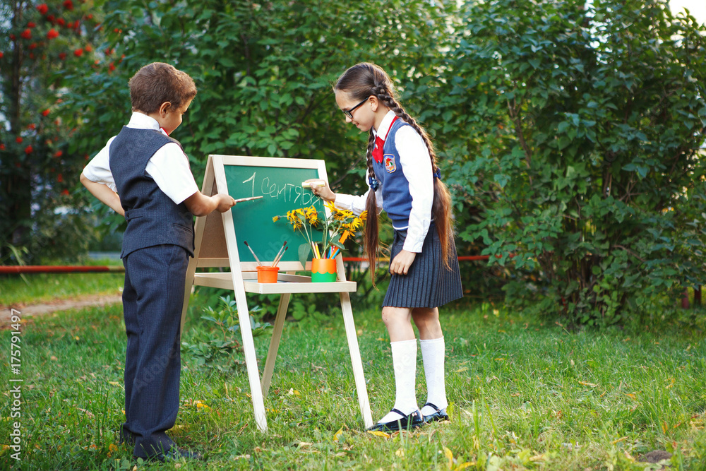 Small pupils a boy and a girl at the blackboard have fun laughing in the Park. copyspace Small pupils a boy and a girl at the blackboard have fun laughing in the Park. copyspace