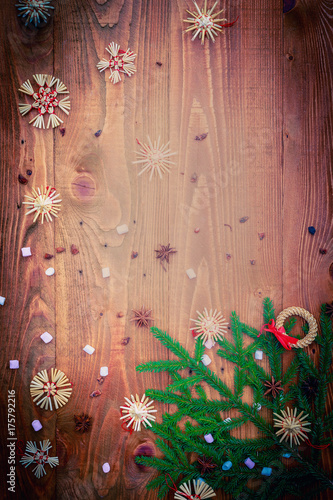 Christmas background with straw decorations, spices, marshmallow on old rustic wooden board, top view, copy space