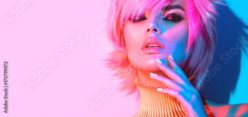Fashion model woman in colorful bright lights with trendy make-up, manicure and haircut