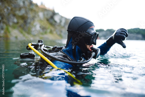Male diver in wetsuit checking equipments before immerse photo