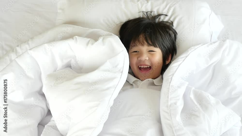 Cute asian child playing hide and seek on white bed slow motion Cute asian child playing hide and seek on white bed slow motion