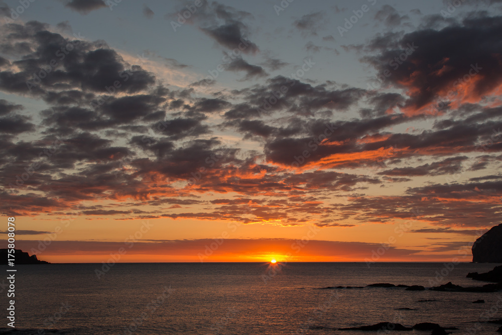 Reddish dawn in the sea and with clouds. Atmospheric phenomena concept