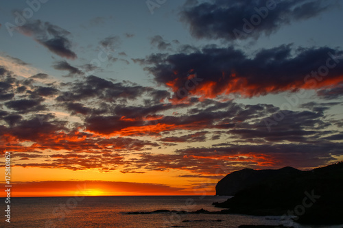 Reddish dawn in the sea and with clouds. Atmospheric phenomena concept