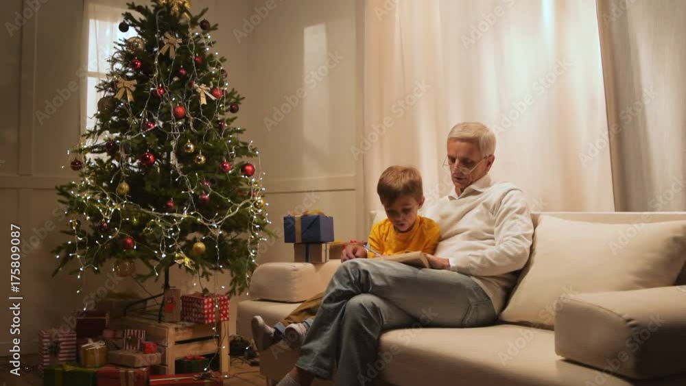 Cheerful retired man and his grandfather preparing Christmas presents Cheerful retired man and his grandfather preparing Christmas presents
