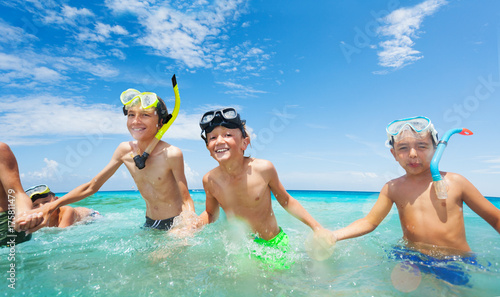 Group of happy boys in scuba mask run into the sea