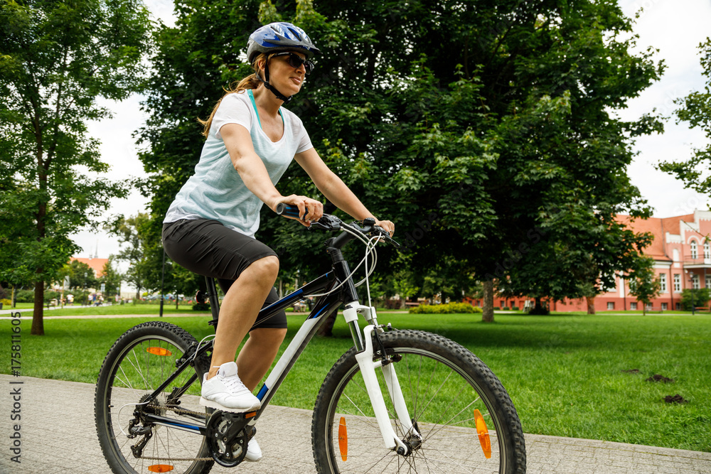 Healthy lifestyle - woman riding bicycle in city park 