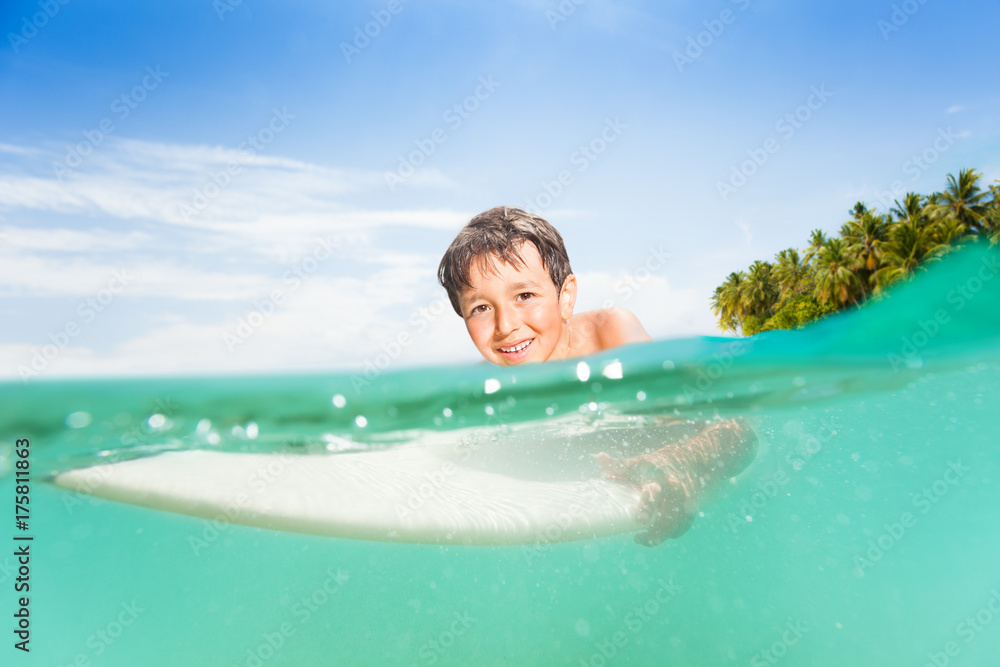 Half underwater image of boy on surfing board