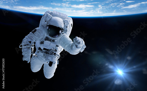 Fototapeta Naklejka Na Ścianę i Meble -  astronaut in orbit of the planet Earth lit by the Sun