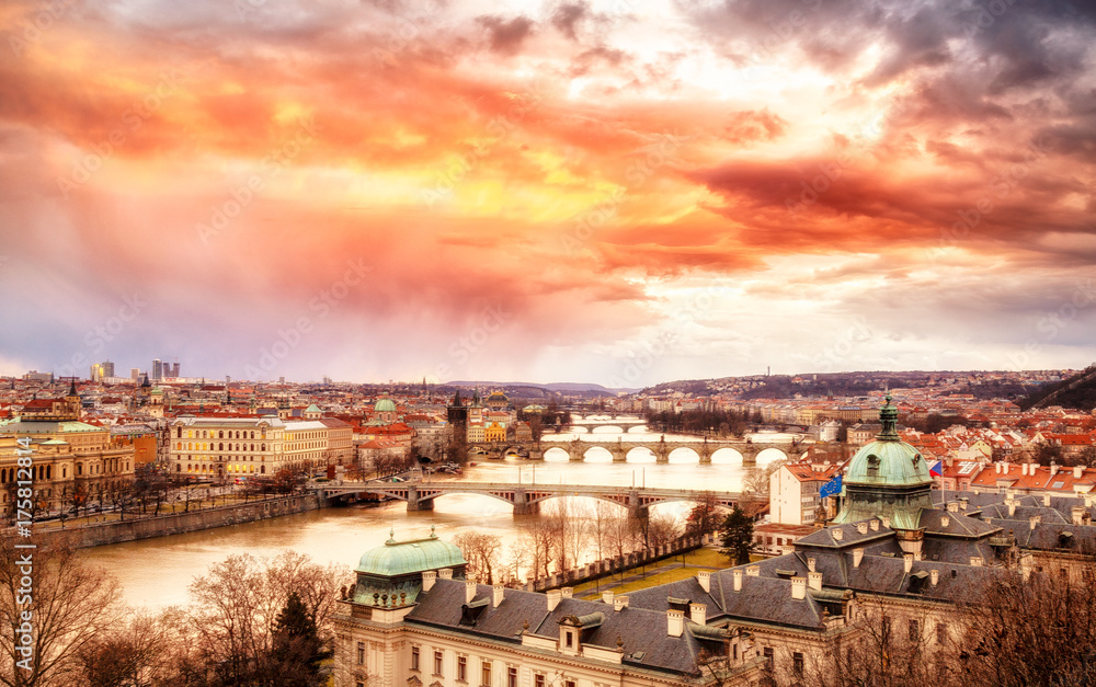 Classic spectacular scenery of Prague. Bridge vista over Vltava river beneath the epic and dramatic sunset sky in winter season. Prague is famous and very popular travel destination city in Europe.