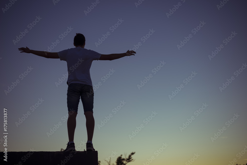 silhouette of a guy divorced in different directions hands on a sunset background without a face.