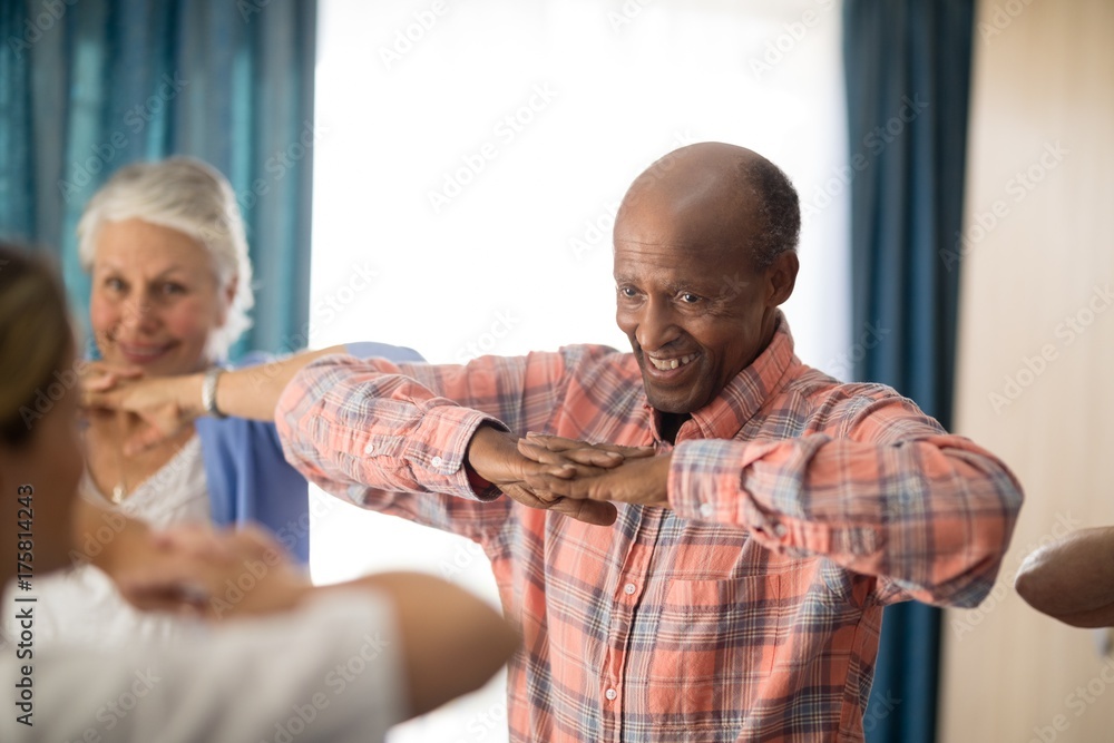 Obraz premium Smiling senior man standing with hands clasped with friends and